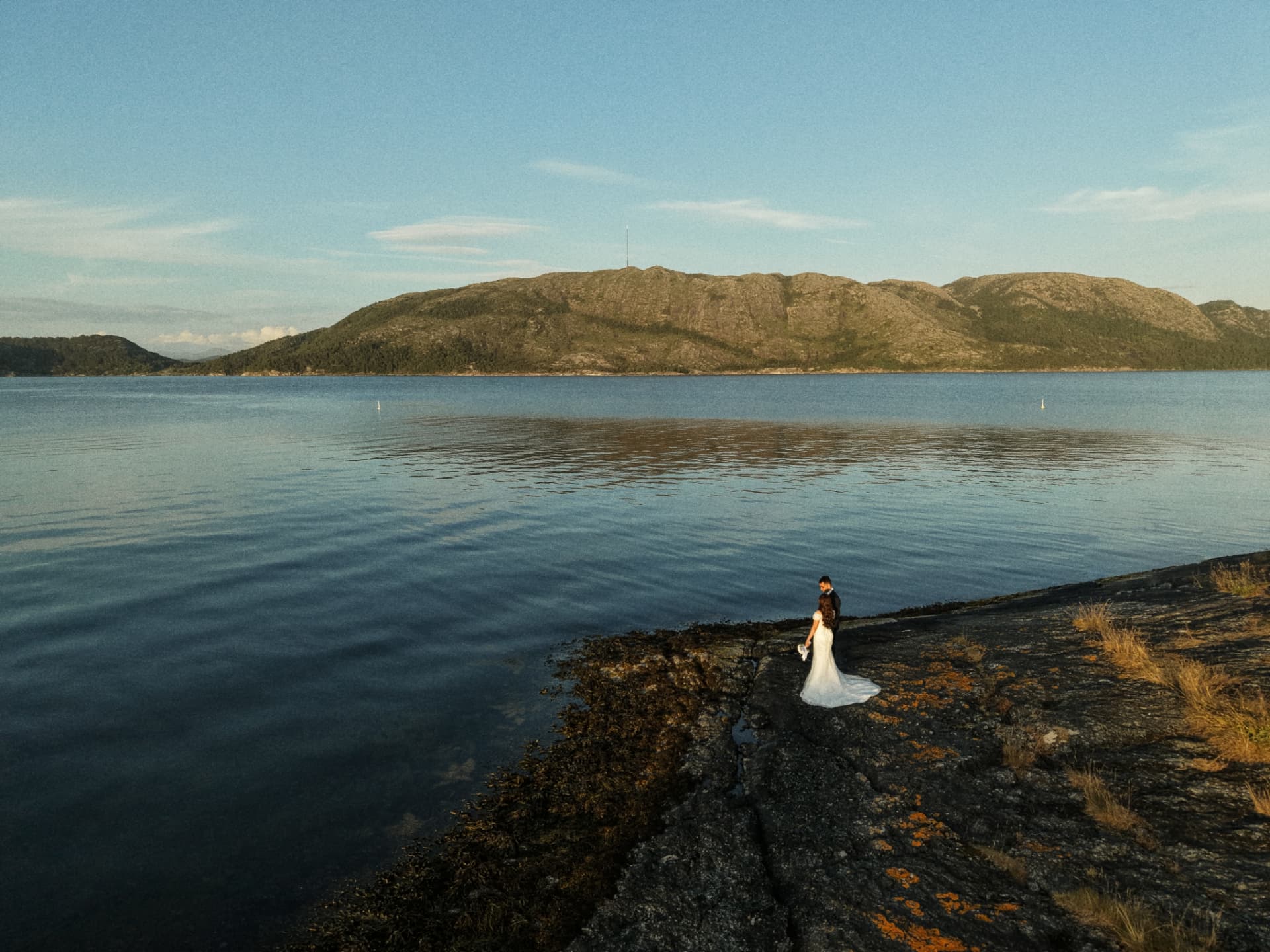 Aerial view of the couple on the shoreline with the mountains behind