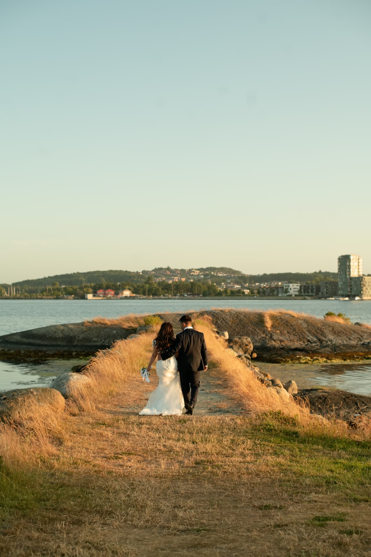 Couple walking the golden headland toward the sea