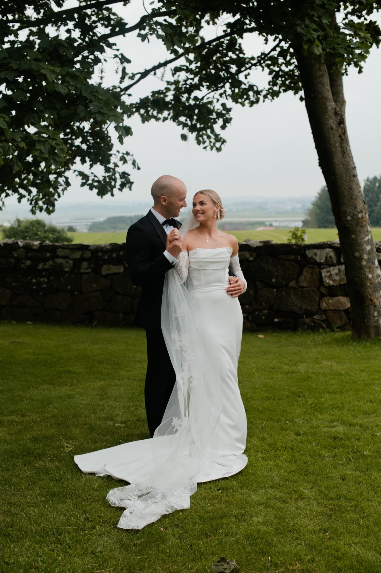 Couple standing together by a stone wall