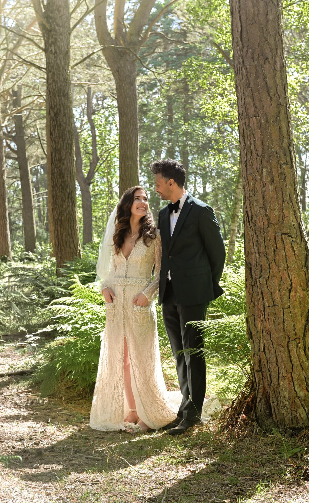 Couple beneath tall pines in the woods
