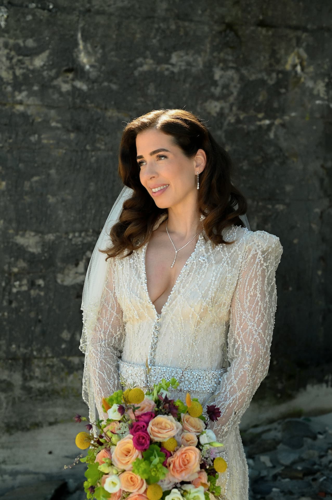 Bride with her bouquet against a stone wall