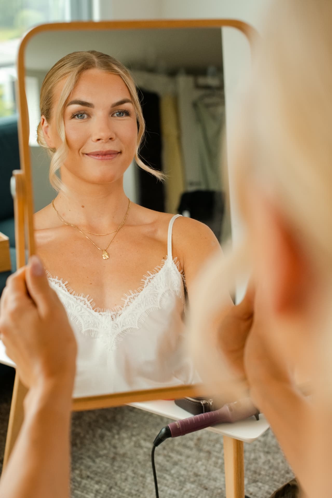 Bride looking into the mirror as her hair is finished