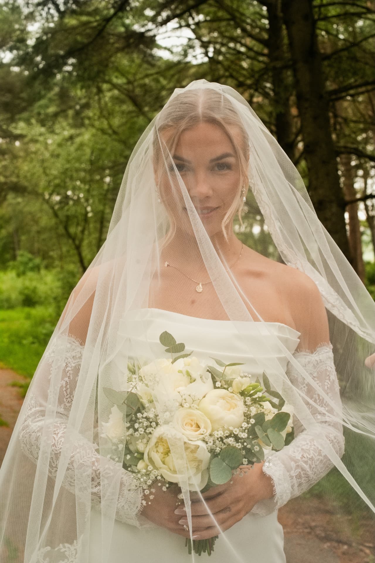 Bride beneath her veil holding her bouquet