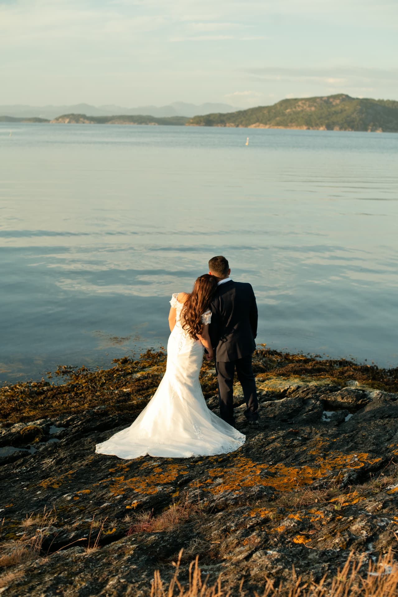 Bride resting her head on the groom's shoulder on the rocks