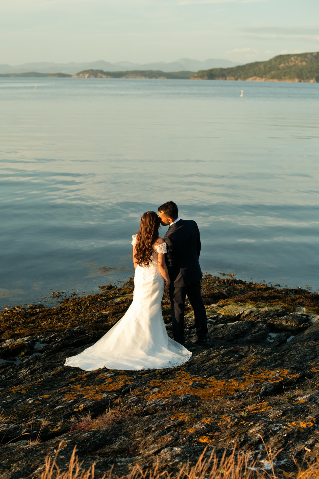 Bride and groom kissing on the rocks at Vaulen Beach