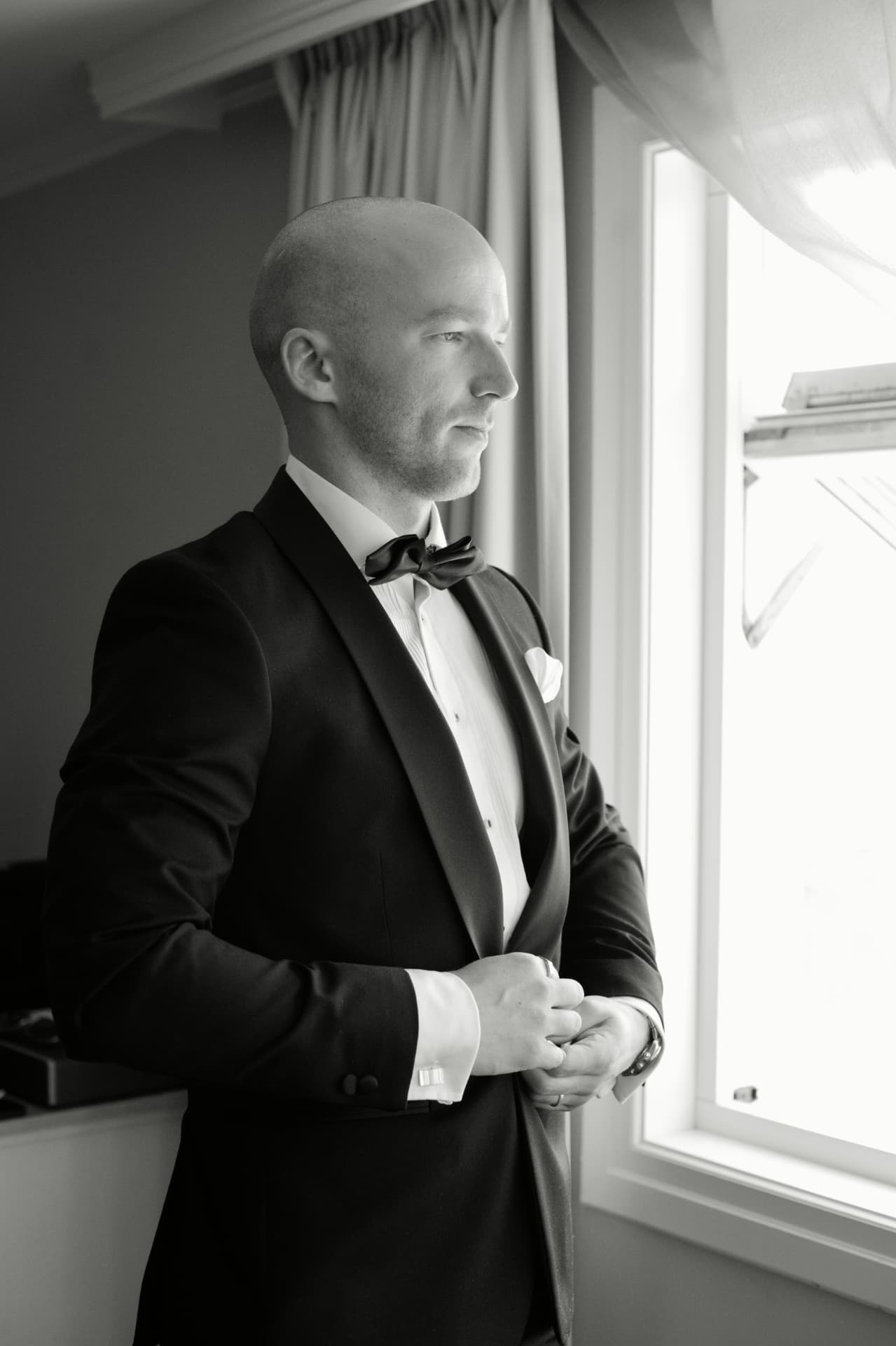 Groom by the window in his tuxedo before the ceremony