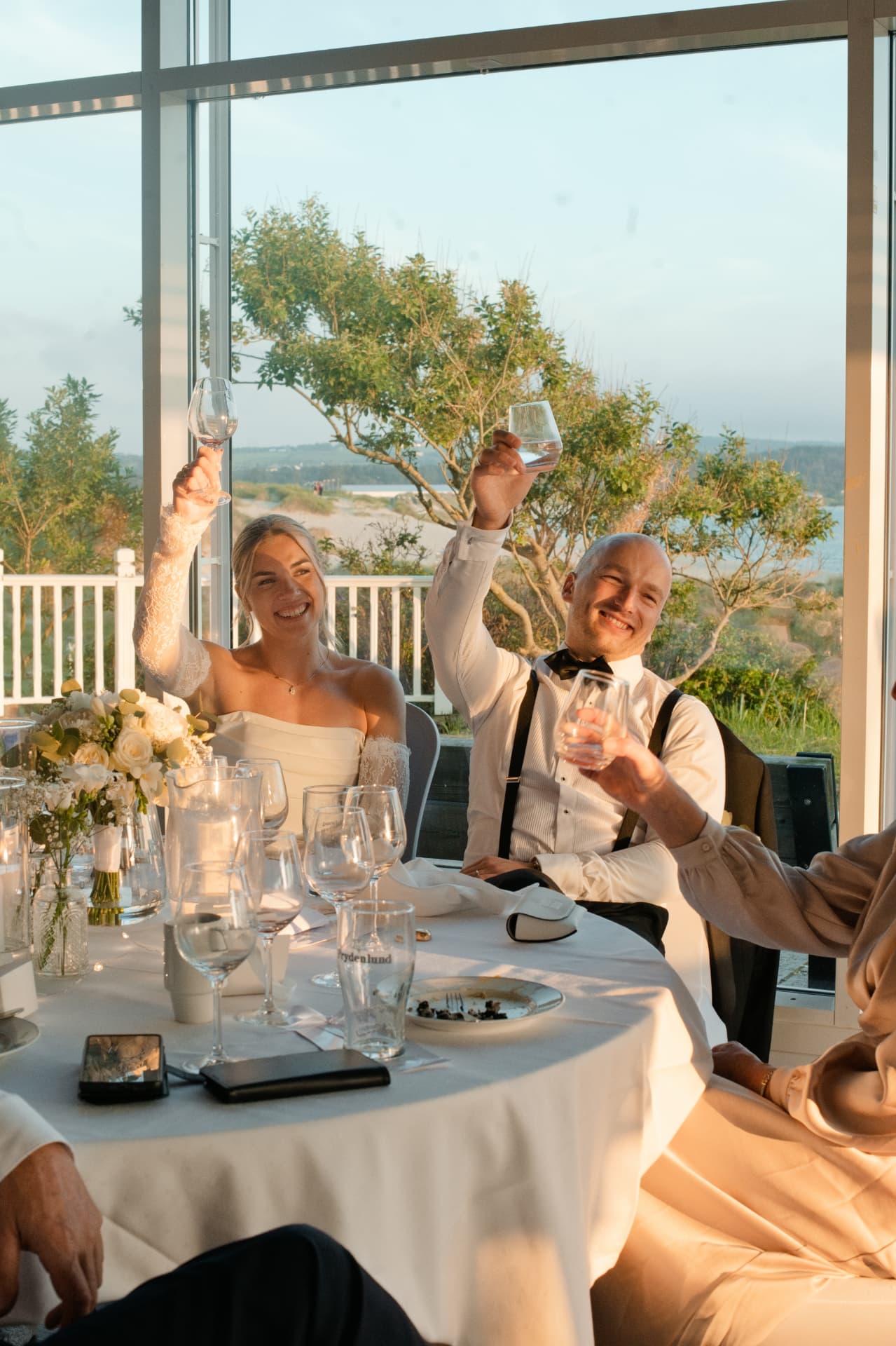 Bride and groom toasting at their table by the sea