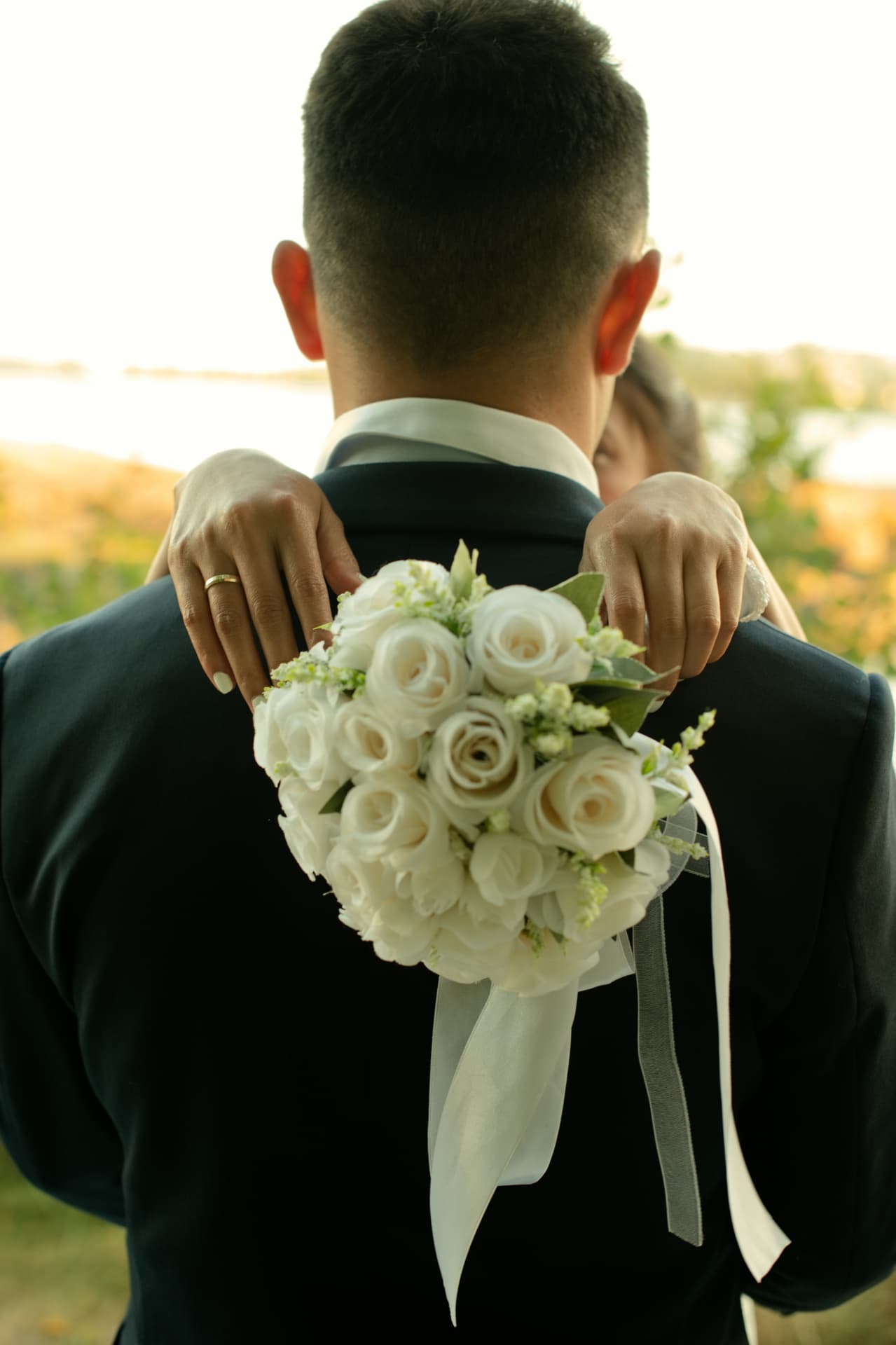Bride's bouquet resting on the groom's shoulder as they embrace