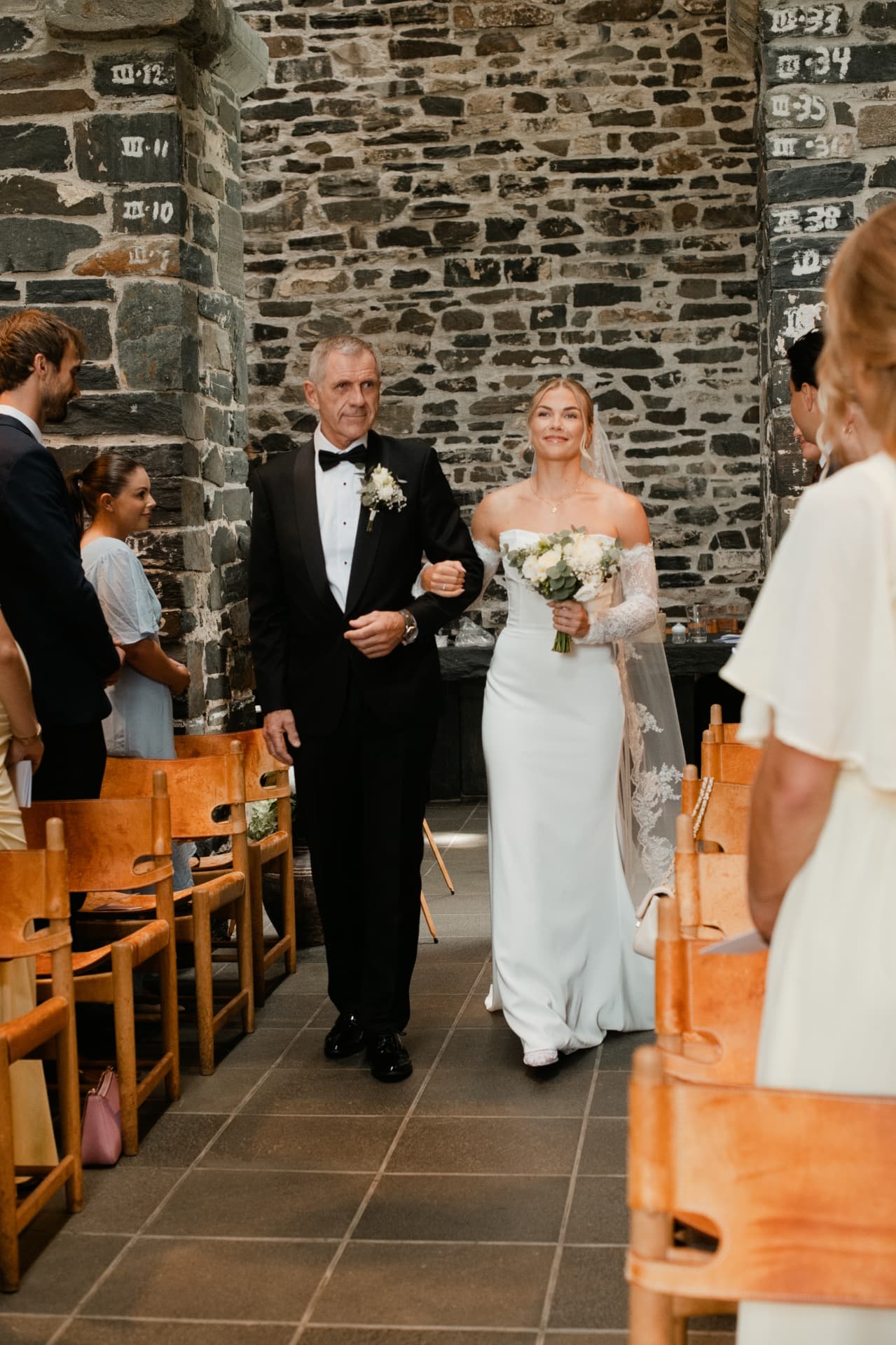 Bride walking down the stone church aisle with her father