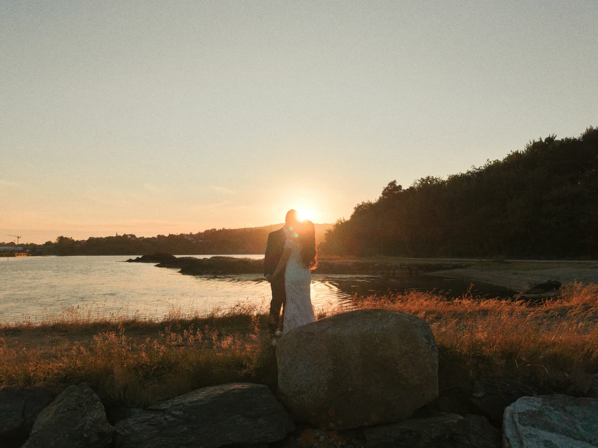 Couple kissing at sunset above the water