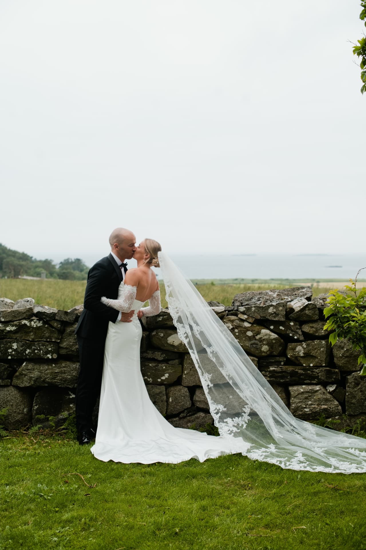 Bride and groom sharing a kiss with the sea behind them at Sola Beach
