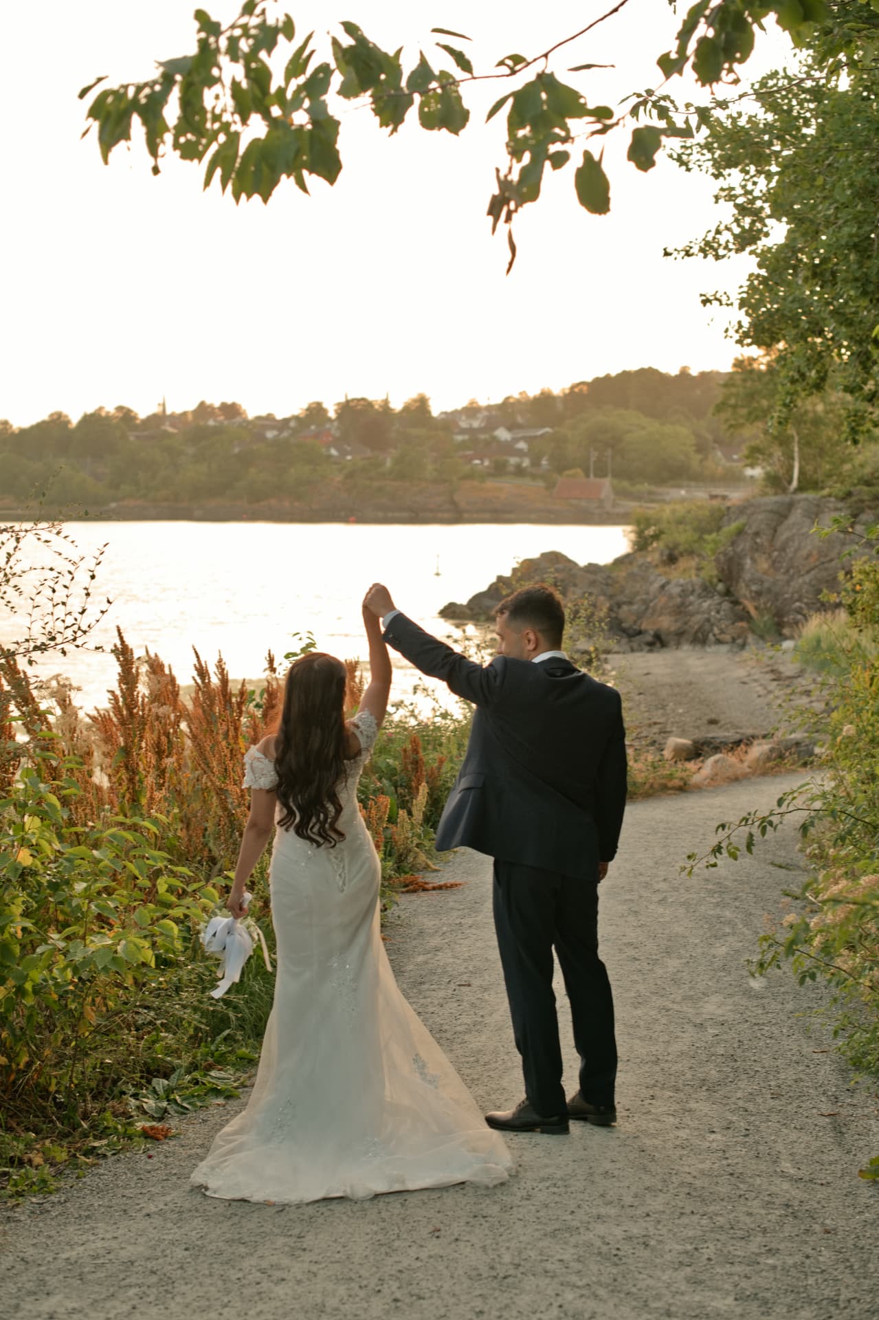 Groom twirling his bride on the path by the sea
