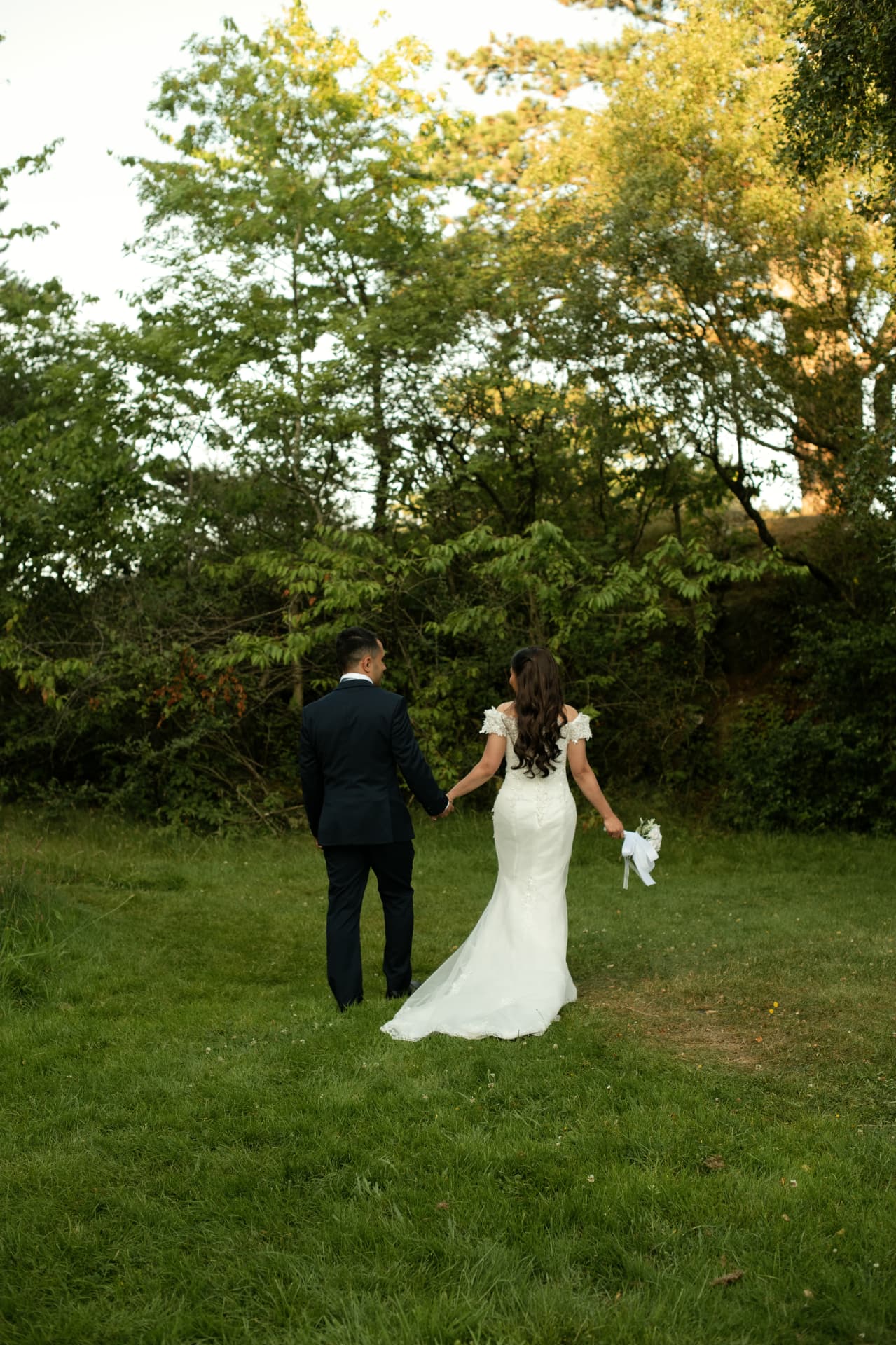 Couple walking hand in hand across the meadow