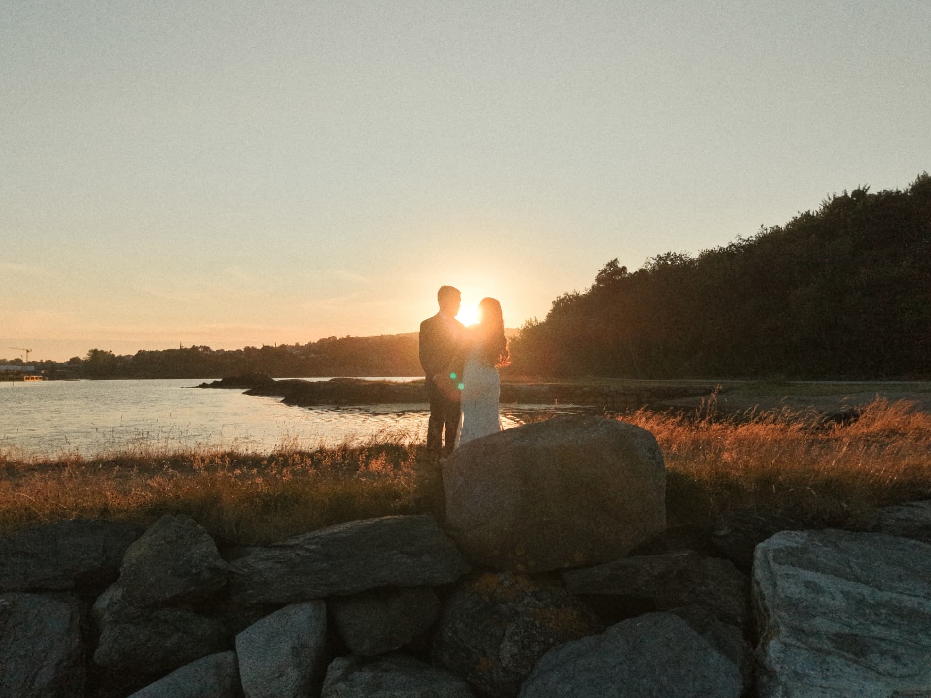 Couple silhouetted against the setting sun by the water